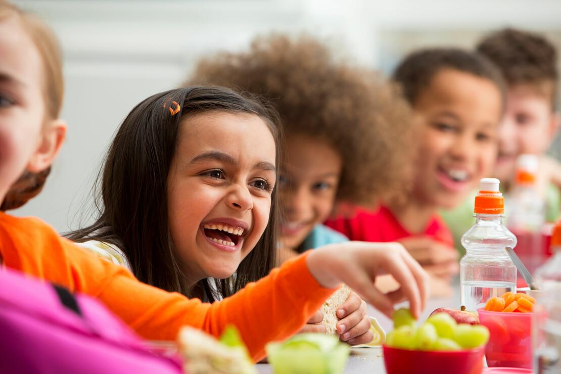 Smiling children sitting at a healthy snack table