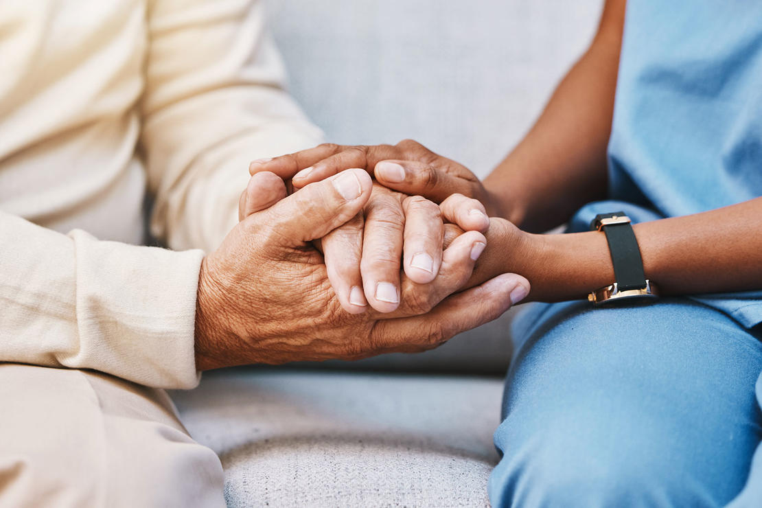 Young physician holding an older patient's hands