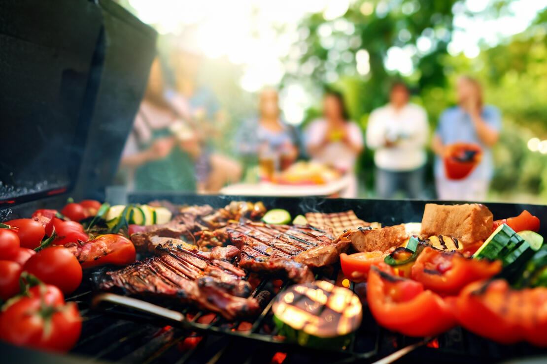 Close up of colorful food on a grill, blurred cookout in background