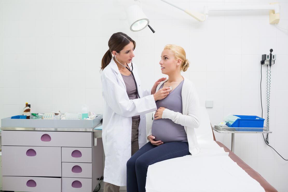 Female doctor auscultating a pregnant woman on an examination table in a hospital
