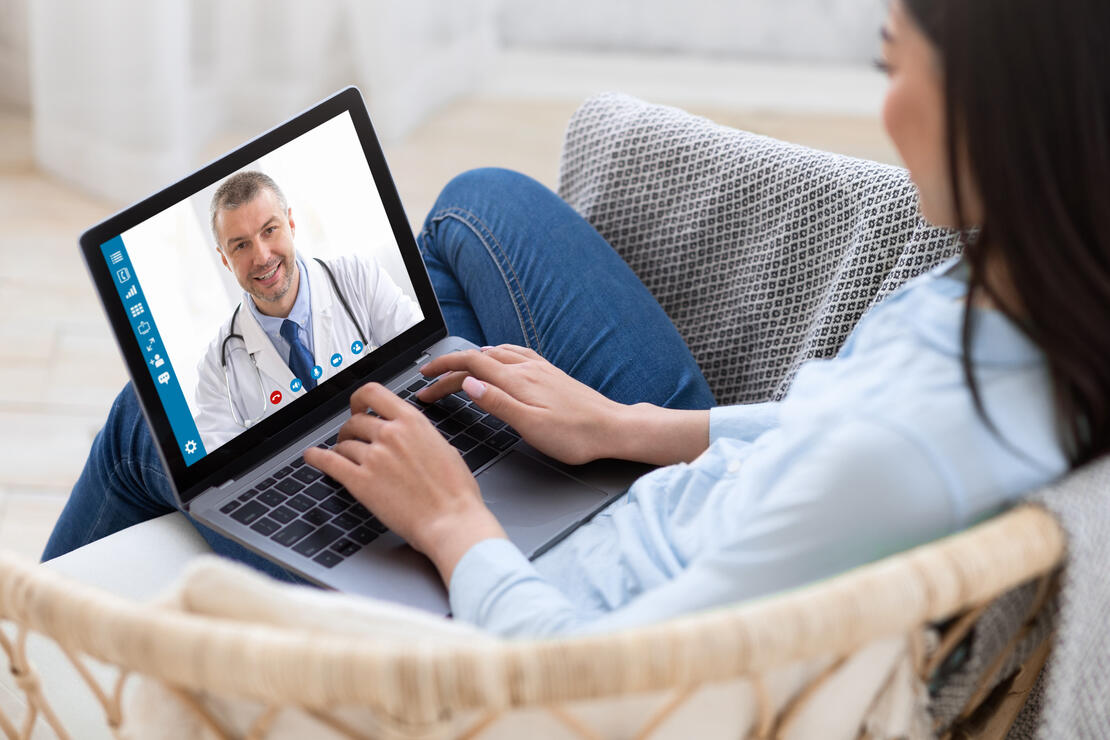 Telemedicine concept. Young lady consulting her doctor on laptop computer, using webcam from home, panorama. Millennial woman communicating with her health practitioner on internet