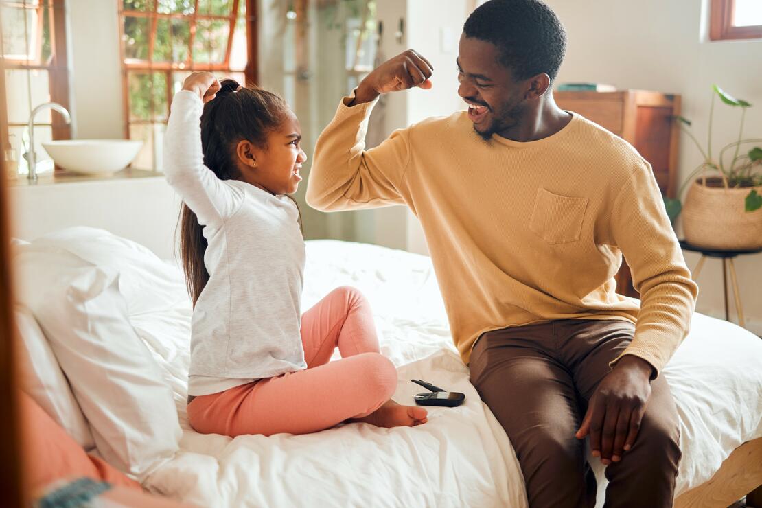 Healthcare, diabetes and father with girl in bedroom show muscles, brave and strong gesture for injury. Love, family home and dad helping child with monitor for glucose, sugar level test and insulin
