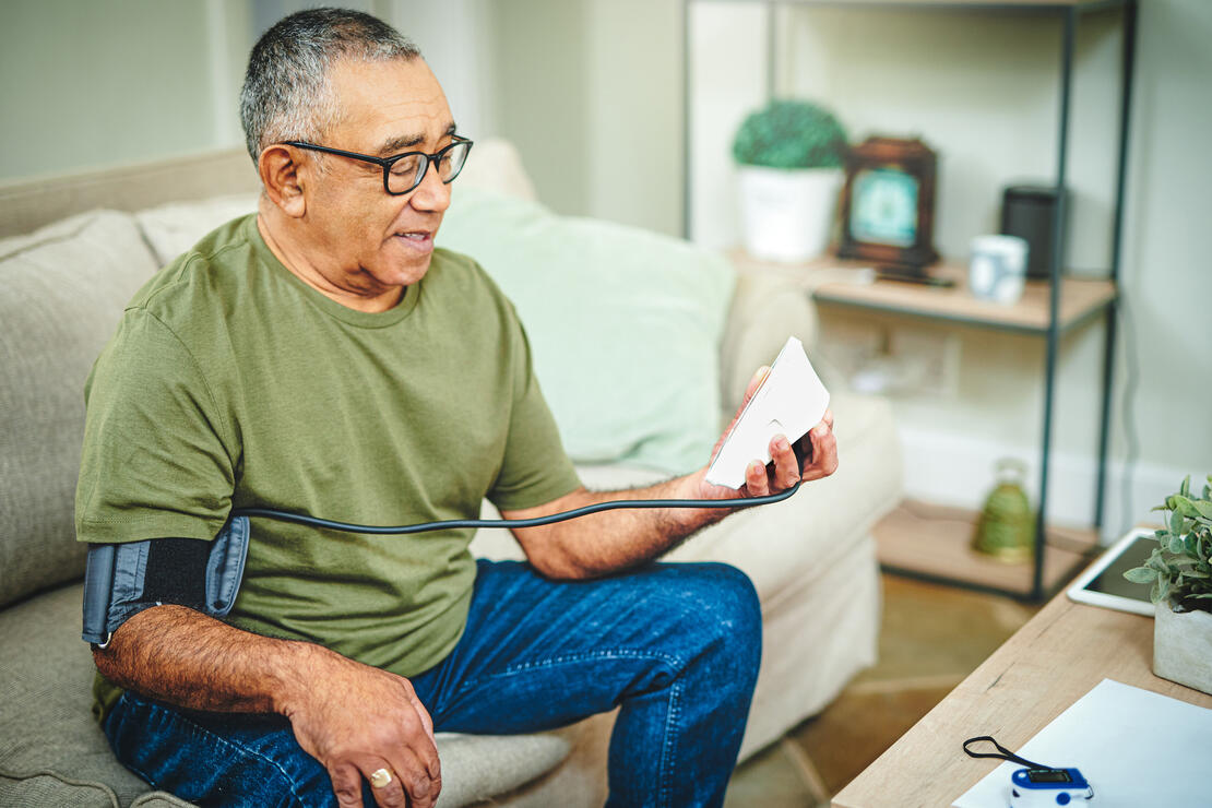 Shot of a senior man using a blood pressure monitor at home