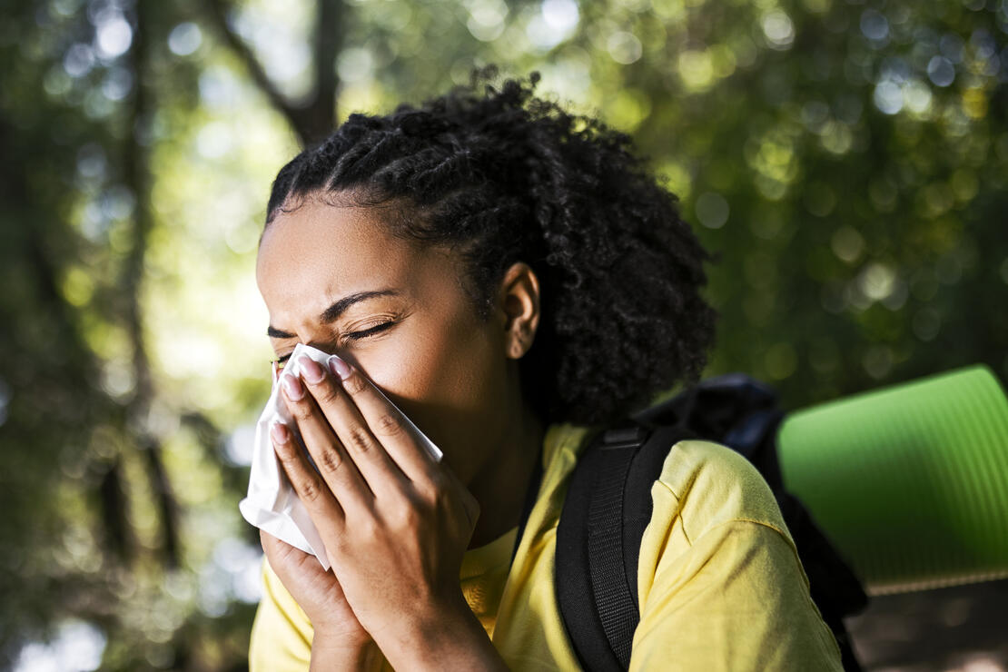 Young woman hiker having allergy sneezing using handkerchief