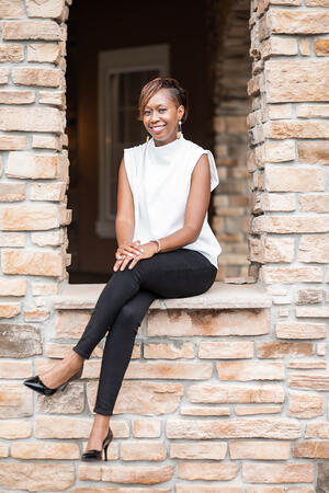 Danielle Randall, Center for Hope's Community Program Manager of Community Violence Intervention Prevention, smiling while sitting on a stone wall.