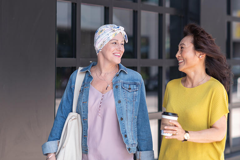 Cancer patient walking with her friend outside.