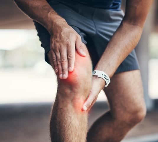 A person holding their sore knee A person holding their sore knee