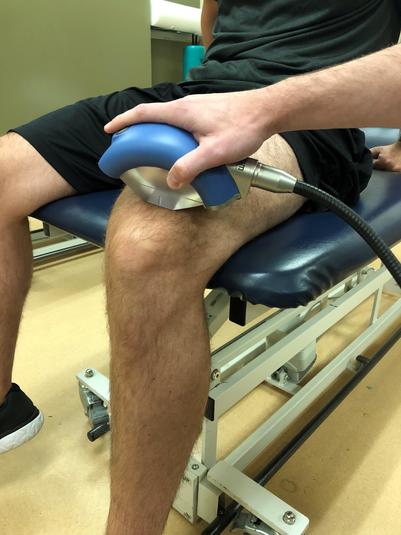 An acoustic wave therapy device on a person's knee
