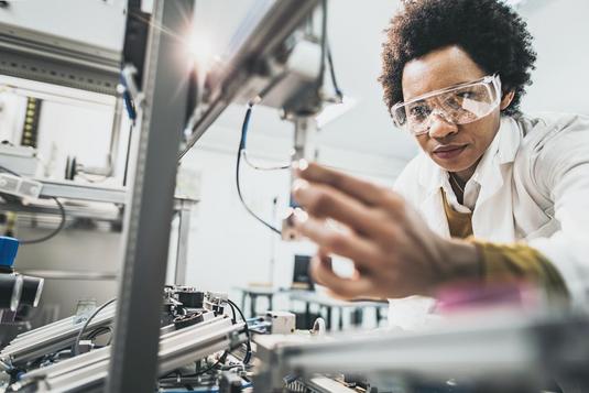 A woman working on robotic machinery in a research lab.