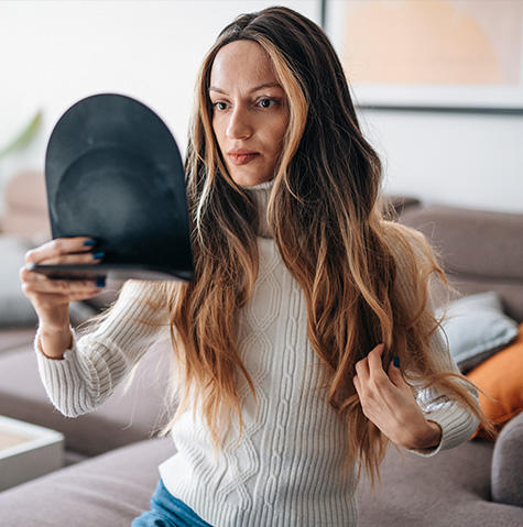 Young woman adjusting her wig after hair loss due to cancer illness.